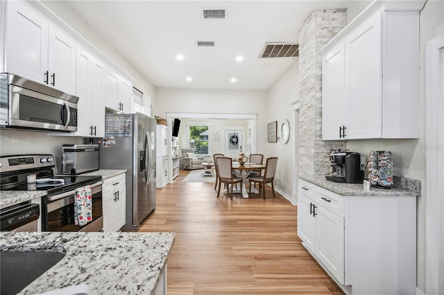 213 Cannon St, Lakeland, FL 33803 - kitchen with stainless steel appliances, white cabinetry, light wood-style flooring, light stone countertops, and recessed lighting