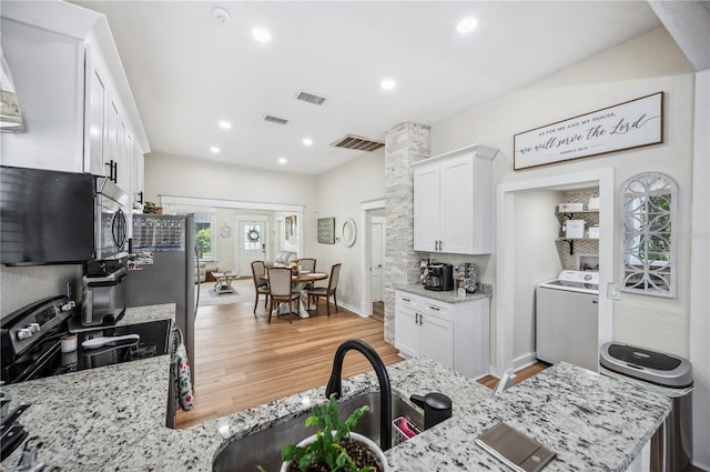 213 Cannon St, Lakeland, FL 33803 - kitchen featuring washer / clothes dryer, stainless steel appliances, white cabinets, light wood-style flooring, and light stone counters