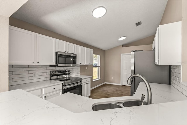 1125 Blackjack Ridge St, Minneola, FL 34715 - kitchen with appliances with stainless steel finishes, light stone countertops, decorative backsplash, white cabinets, and lofted ceiling