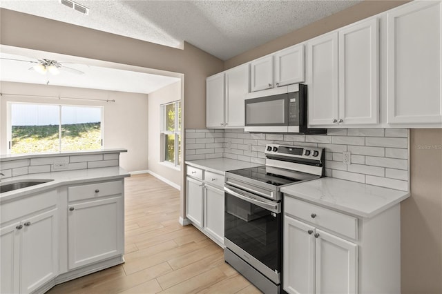 1125 Blackjack Ridge St, Minneola, FL 34715 - kitchen with stainless steel appliances, tasteful backsplash, white cabinetry, and a textured ceiling
