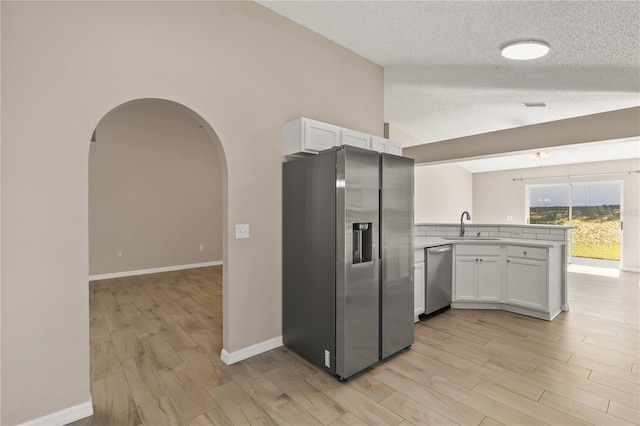 1125 Blackjack Ridge St, Minneola, FL 34715 - kitchen featuring stainless steel appliances, a peninsula, white cabinets, arched walkways, and a textured ceiling