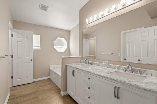1125 Blackjack Ridge St, Minneola, FL 34715 - bathroom featuring wood finished floors, double vanity, and a garden tub