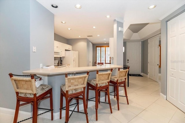 3608 54th Dr W Unit 202, Bradenton, FL 34210 - kitchen with white appliances, a kitchen breakfast bar, a peninsula, recessed lighting, and white cabinetry