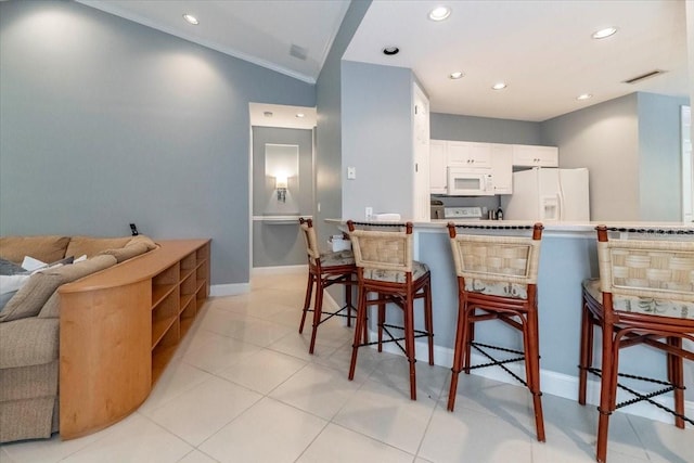 3608 54th Dr W Unit 202, Bradenton, FL 34210 - kitchen with white appliances, a kitchen bar, white cabinets, recessed lighting, and open floor plan