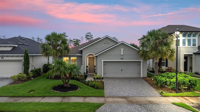 180 Azure Mist Way, Daytona Beach, FL 32124 - view of front of house with stucco siding, decorative driveway, a garage, and a yard