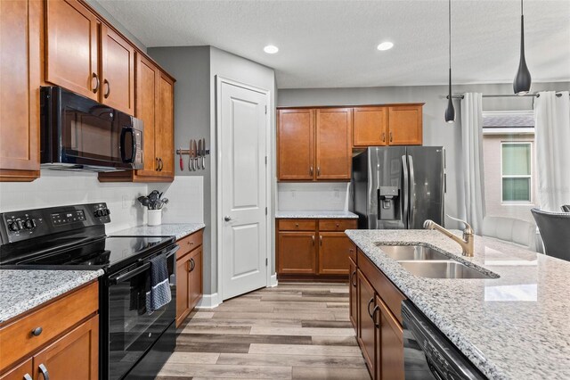 180 Azure Mist Way, Daytona Beach, FL 32124 - kitchen with black appliances, light wood-style flooring, brown cabinets, light stone counters, and decorative backsplash