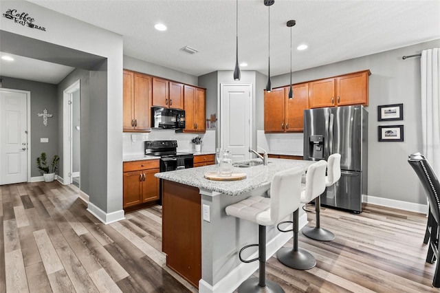 180 Azure Mist Way, Daytona Beach, FL 32124 - kitchen featuring black appliances, brown cabinets, light wood-style flooring, recessed lighting, and hanging light fixtures