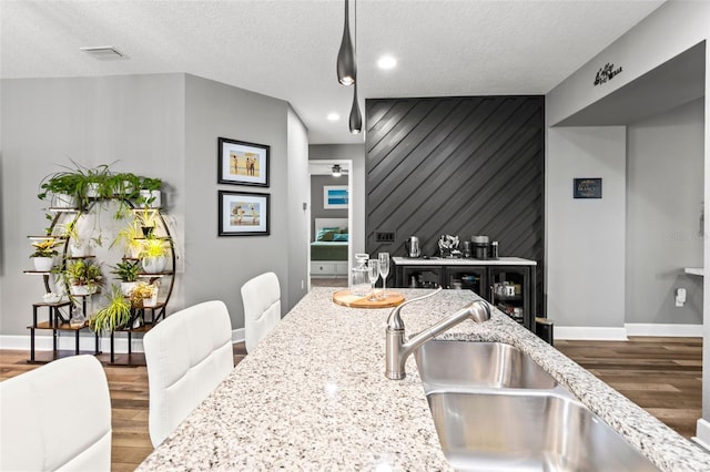 180 Azure Mist Way, Daytona Beach, FL 32124 - kitchen featuring an accent wall, light stone countertops, wood finished floors, a textured ceiling, and recessed lighting