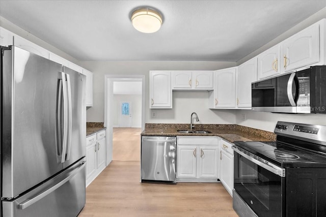 405 S 7th Ave, Bartow, FL 33830 - kitchen with appliances with stainless steel finishes, white cabinets, light wood finished floors, and dark stone countertops