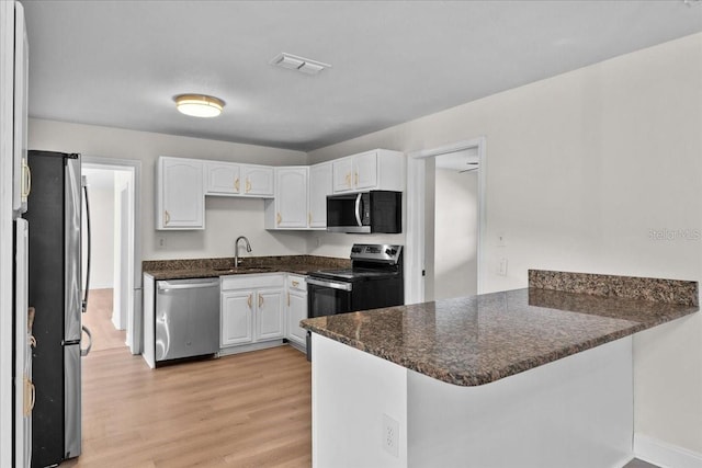 405 S 7th Ave, Bartow, FL 33830 - kitchen featuring appliances with stainless steel finishes, a peninsula, white cabinets, and light wood-style flooring