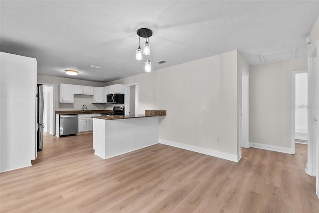 405 S 7th Ave, Bartow, FL 33830 - kitchen with stainless steel appliances, a peninsula, white cabinets, light wood finished floors, and pendant lighting