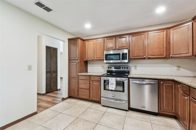849 Rockingham Rd, Lakeland, FL 33809 - kitchen featuring appliances with stainless steel finishes, light tile patterned floors, recessed lighting, and brown cabinets