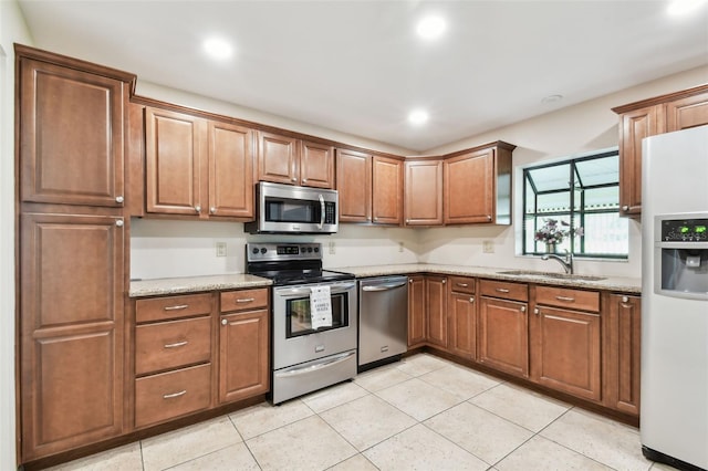 849 Rockingham Rd, Lakeland, FL 33809 - kitchen with stainless steel appliances, light stone counters, light tile patterned floors, brown cabinetry, and recessed lighting