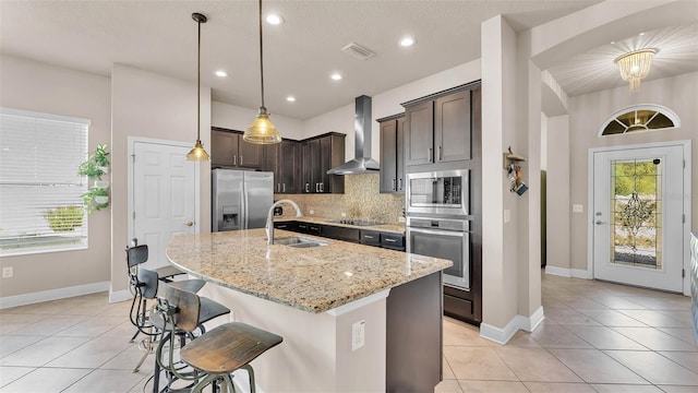 11825 Frost Aster Dr, Riverview, FL 33579 - kitchen featuring stainless steel appliances, wall chimney range hood, dark brown cabinets, tasteful backsplash, and light tile patterned floors
