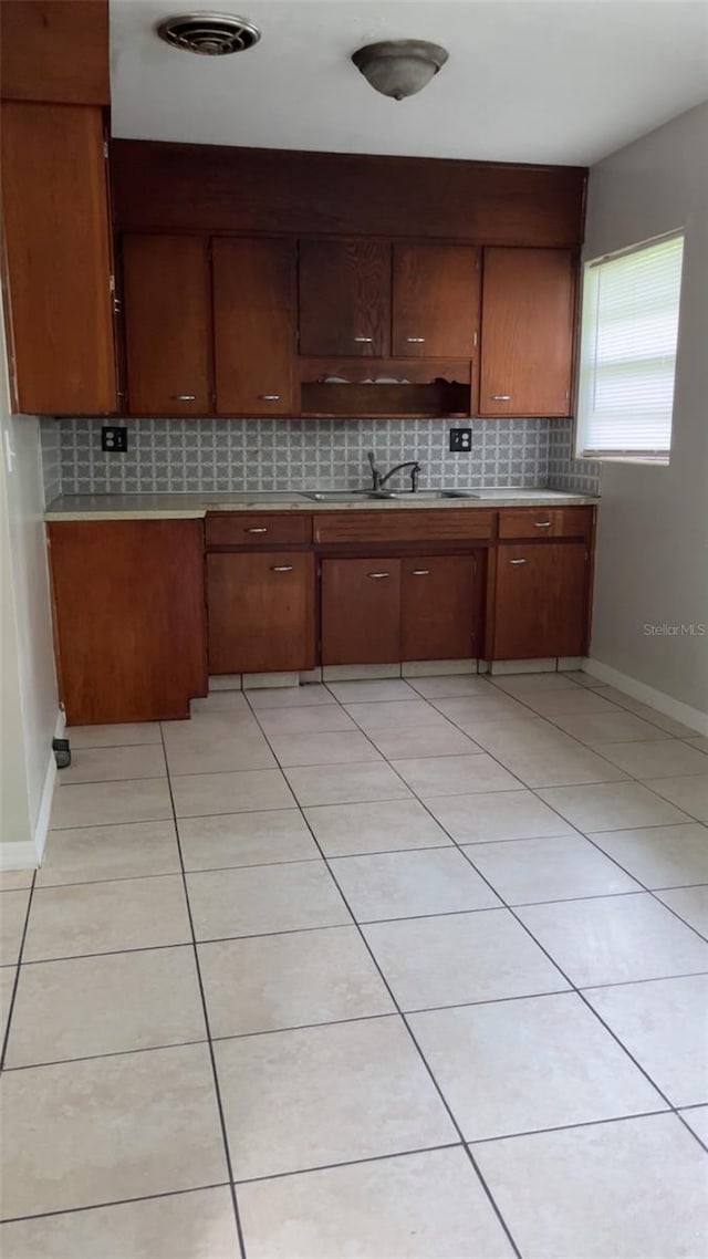 2708 Dixie Rd, Lakeland, FL 33801 - kitchen featuring backsplash, light countertops, light tile patterned floors, and brown cabinetry