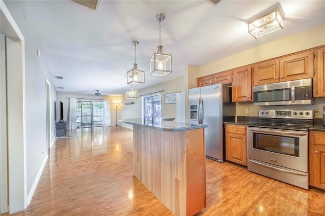 1523 Mariner Rd, Lakeland, FL 33803 - kitchen featuring stainless steel appliances, light wood-style flooring, decorative light fixtures, dark stone countertops, and a center island
