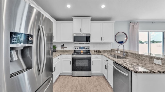 3739 Peregrine Way, Lakeland, FL 33811 - kitchen featuring stainless steel appliances, a peninsula, white cabinets, light stone counters, and backsplash