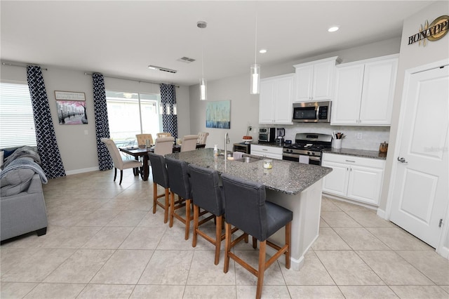 1044 Oliveto Verdi Ct, Brandon, FL 33511 - kitchen with appliances with stainless steel finishes, light tile patterned flooring, a breakfast bar, white cabinets, and dark stone countertops