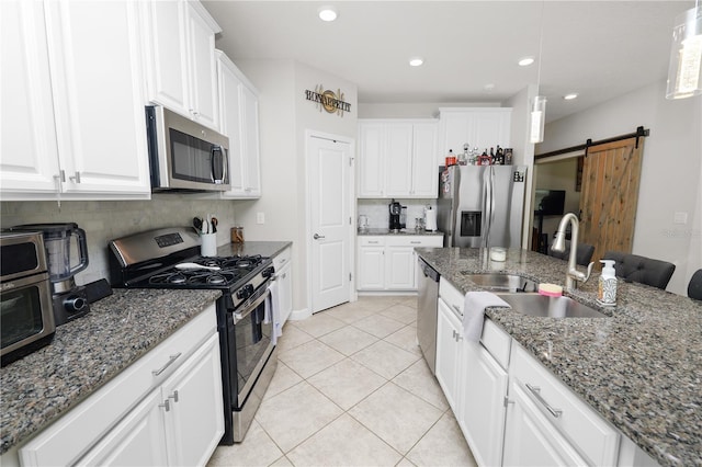 1044 Oliveto Verdi Ct, Brandon, FL 33511 - kitchen with appliances with stainless steel finishes, light tile patterned flooring, decorative backsplash, a barn door, and white cabinets