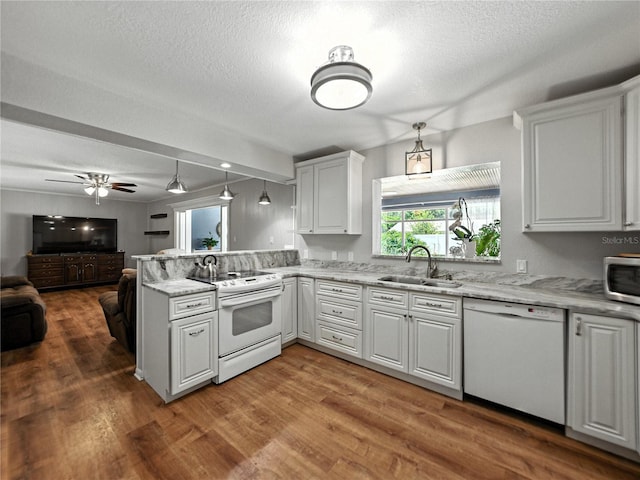 1232 Fairlee St, Lakeland, FL 33813 - kitchen with white appliances, open floor plan, a textured ceiling, a peninsula, and white cabinetry