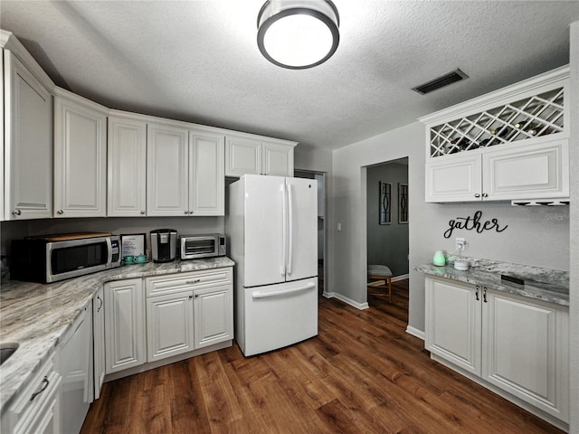 1232 Fairlee St, Lakeland, FL 33813 - kitchen with freestanding refrigerator, stainless steel microwave, white cabinetry, dark wood-style floors, and a textured ceiling