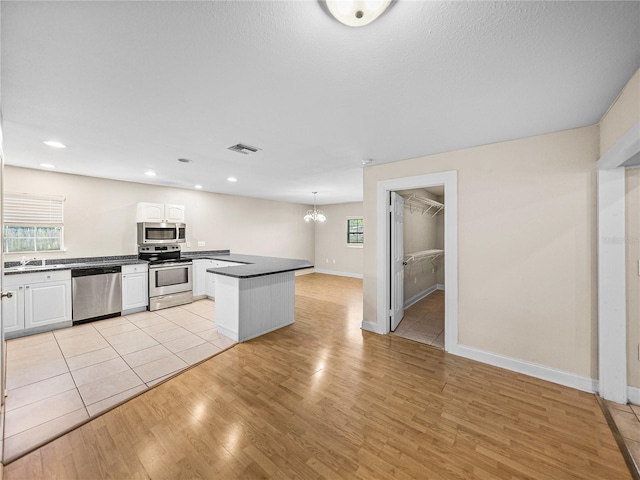 4230 Viola Rd, Lakeland, FL 33810 - kitchen with stainless steel appliances, light wood-style floors, dark countertops, white cabinetry, and recessed lighting