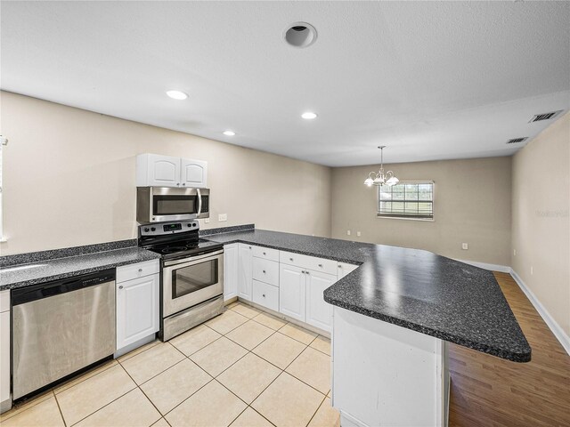 4230 Viola Rd, Lakeland, FL 33810 - kitchen featuring appliances with stainless steel finishes, a peninsula, dark countertops, a chandelier, and white cabinetry