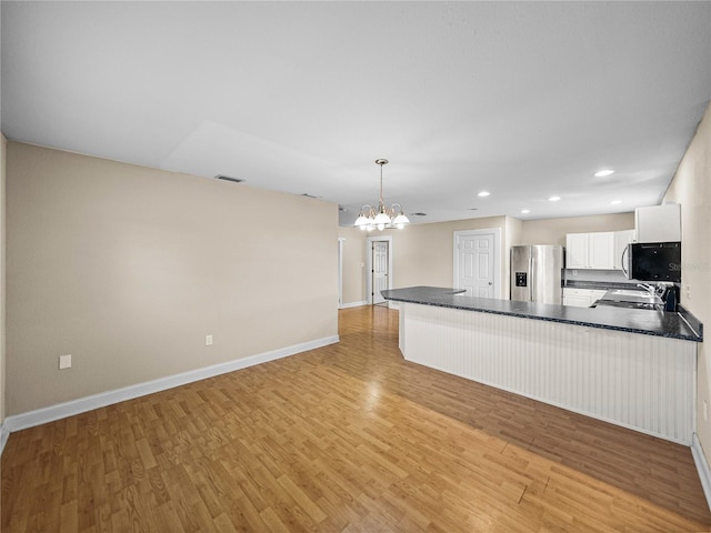 4230 Viola Rd, Lakeland, FL 33810 - kitchen with stainless steel fridge with ice dispenser, dark countertops, a chandelier, a peninsula, and black microwave