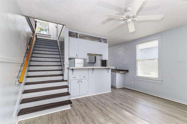 121 F Ave SW, Winter Haven, FL 33880 - kitchen with light wood-style floors, plenty of natural light, white cabinetry, and a peninsula