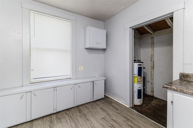 121 F Ave SW, Winter Haven, FL 33880 - kitchen with water heater, white cabinets, and light wood finished floors