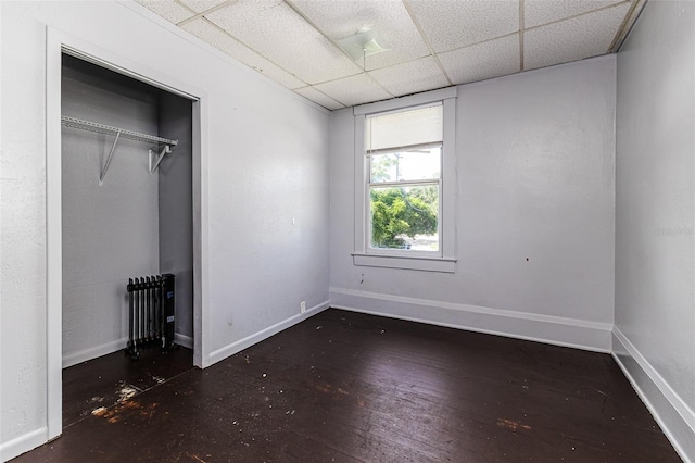 121 F Ave SW, Winter Haven, FL 33880 - unfurnished bedroom featuring a drop ceiling, radiator, hardwood / wood-style flooring, and a closet