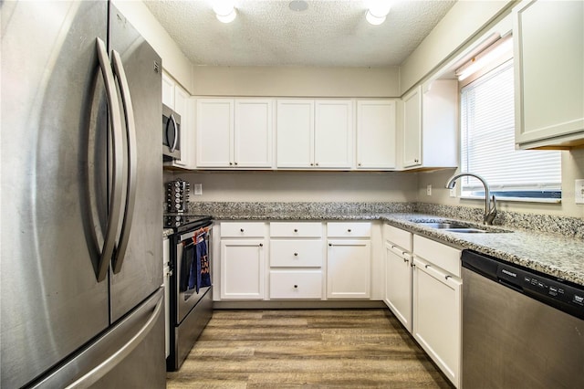 3542 Raintree Ct, Lakeland, FL 33803 - kitchen featuring stainless steel appliances, dark wood-style flooring, a textured ceiling, white cabinets, and light stone counters