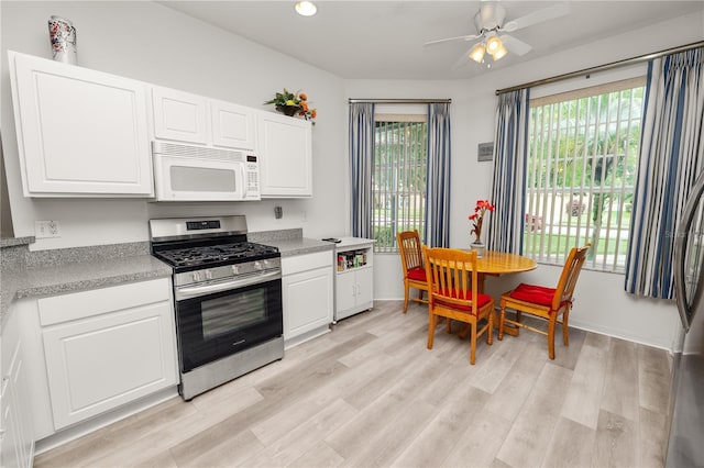 4242 Whistlewood Cir, Lakeland, FL 33811 - kitchen with stainless steel range with gas stovetop, white microwave, light countertops, a ceiling fan, and white cabinets