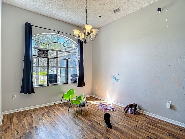 173 Portland Ave, Spring Hill, FL 34606 - spare room featuring healthy amount of natural light, a textured ceiling, wood finished floors, and a chandelier