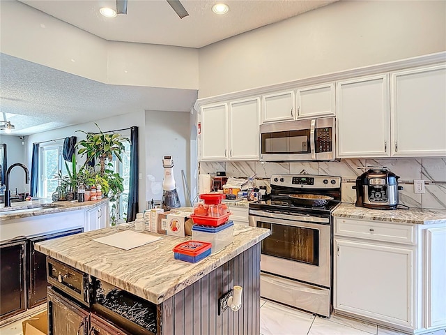 173 Portland Ave, Spring Hill, FL 34606 - kitchen featuring appliances with stainless steel finishes, white cabinetry, tasteful backsplash, a kitchen island, and a textured ceiling