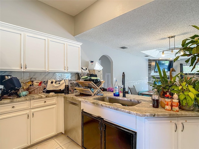 173 Portland Ave, Spring Hill, FL 34606 - kitchen with a peninsula, light stone counters, white cabinetry, arched walkways, and light tile patterned floors