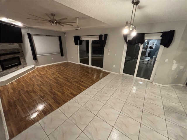 173 Portland Ave, Spring Hill, FL 34606 - unfurnished living room with a fireplace with raised hearth, a textured ceiling, ceiling fan, and wood finished floors