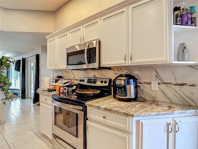 173 Portland Ave, Spring Hill, FL 34606 - kitchen with appliances with stainless steel finishes, decorative backsplash, white cabinets, light stone countertops, and light marble finish floors