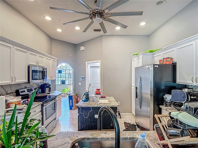 173 Portland Ave, Spring Hill, FL 34606 - kitchen with stainless steel appliances, white cabinets, a kitchen island, ceiling fan, and a towering ceiling
