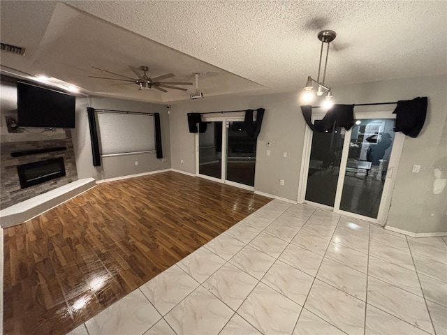 173 Portland Ave, Spring Hill, FL 34606 - unfurnished living room featuring a textured ceiling, ceiling fan, a fireplace with raised hearth, and wood finished floors