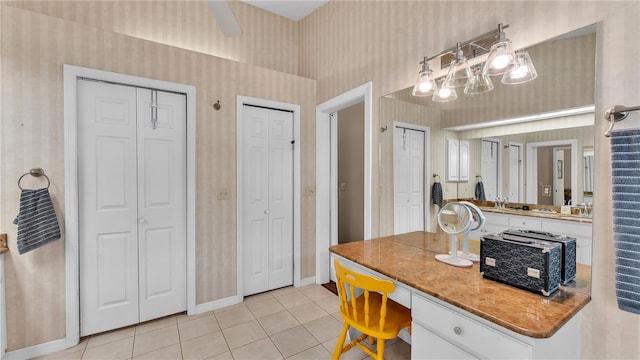 5819 Hollyhock Dr, Lakeland, FL 33813 - kitchen featuring wallpapered walls, light tile patterned floors, white cabinets, built in desk, and light countertops