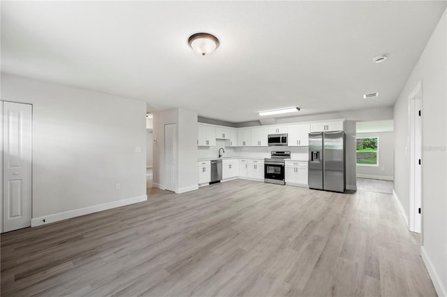 2633 Keysville Dr, Lithia, FL 33547 - kitchen with stainless steel appliances, light countertops, light wood-style floors, white cabinets, and decorative backsplash