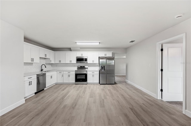 2633 Keysville Dr, Lithia, FL 33547 - kitchen featuring stainless steel appliances, light countertops, decorative backsplash, light wood-type flooring, and white cabinets