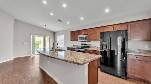 4143 Red Fern Ln, Lakeland, FL 33811 - kitchen with stainless steel appliances, vaulted ceiling, light wood-style flooring, a kitchen island with sink, and recessed lighting