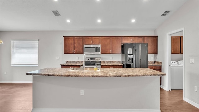 4143 Red Fern Ln, Lakeland, FL 33811 - kitchen with appliances with stainless steel finishes, washer and clothes dryer, a kitchen island with sink, wood finished floors, and recessed lighting