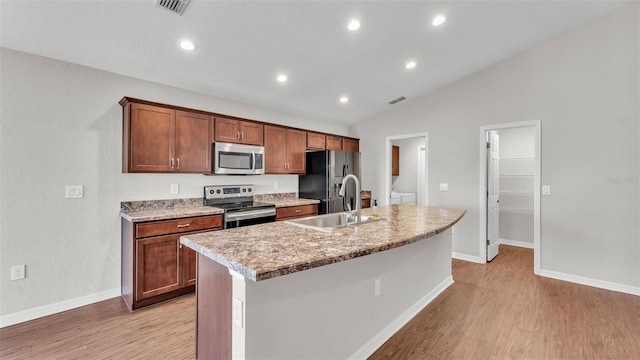 4143 Red Fern Ln, Lakeland, FL 33811 - kitchen with appliances with stainless steel finishes, lofted ceiling, an island with sink, light wood finished floors, and light countertops