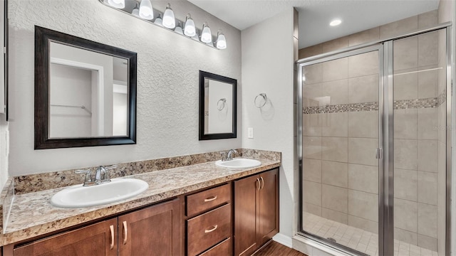 4143 Red Fern Ln, Lakeland, FL 33811 - bathroom featuring double vanity, a stall shower, a textured wall, and wood finished floors