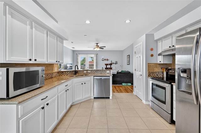 1026 Mohawk Ave NW, Palm Bay, FL 32907 - kitchen with appliances with stainless steel finishes, under cabinet range hood, a peninsula, decorative backsplash, and a ceiling fan