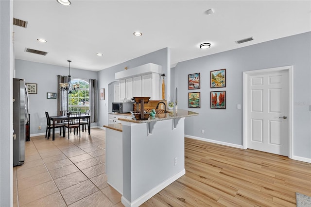 1026 Mohawk Ave NW, Palm Bay, FL 32907 - kitchen featuring stainless steel appliances, a peninsula, white cabinets, recessed lighting, and light stone counters