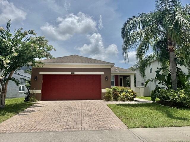 13303 Moss Park Ridge Dr, Orlando, FL 32832 - ranch-style home with stucco siding, decorative driveway, an attached garage, and a front lawn
